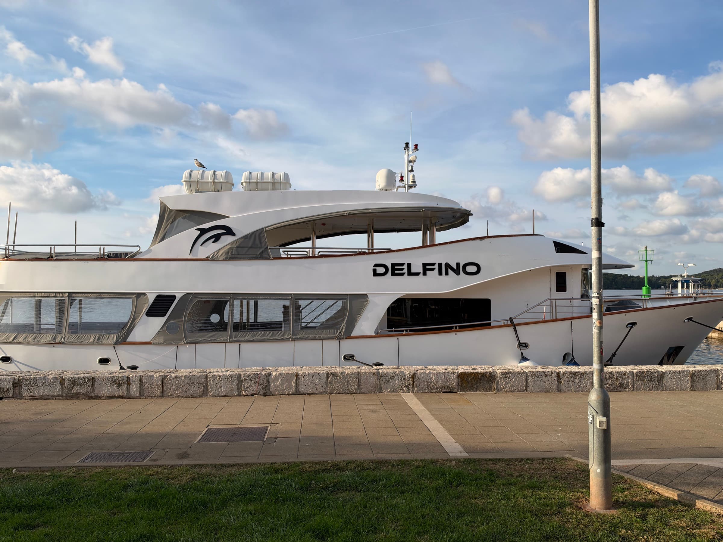 Delfino, a white motor yacht with a black dolphin on her flank, moored on the Rovinj riva
