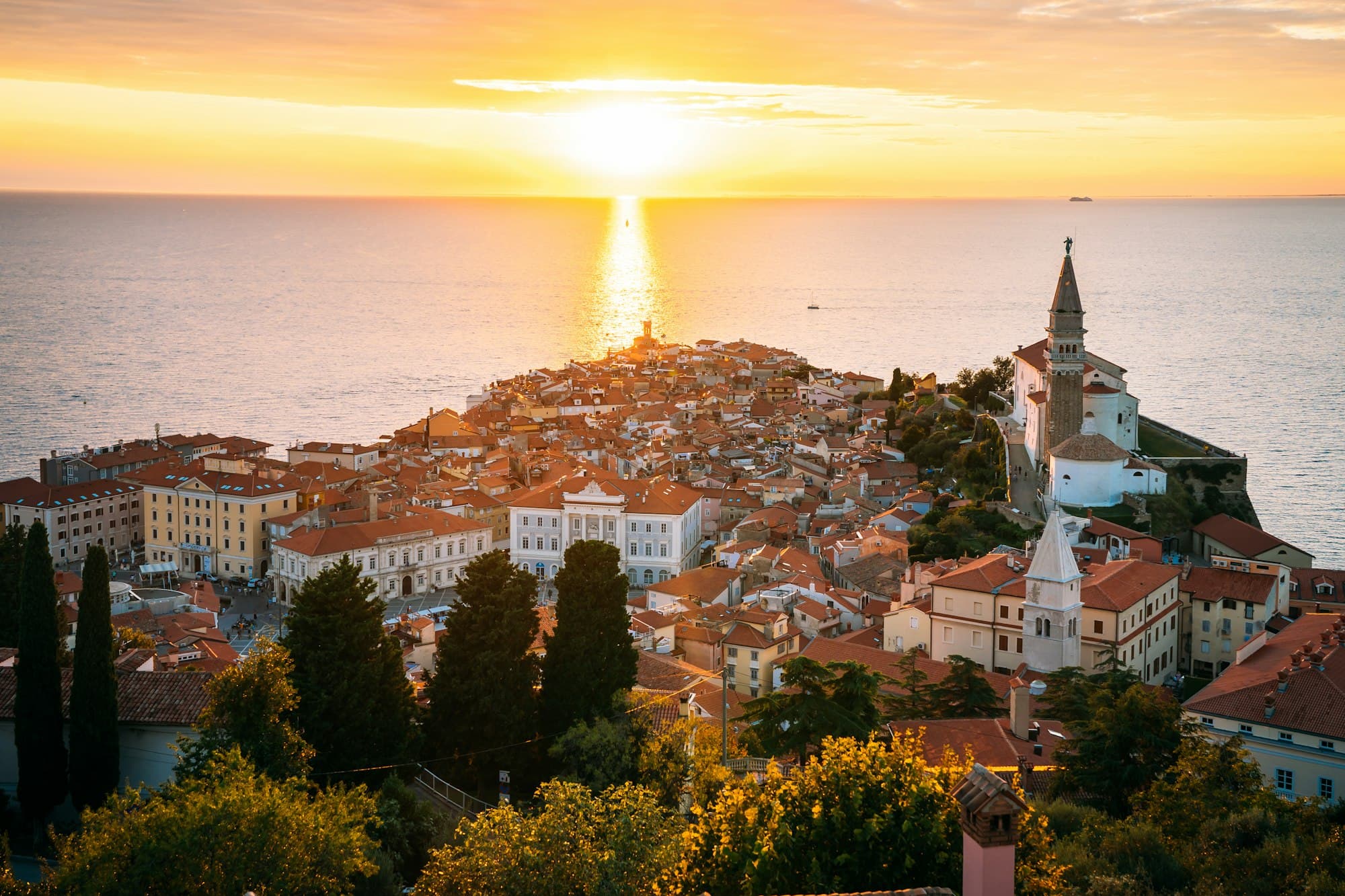 Terracotta roofs of Rovinj glowing at sunset, the sea lit gold behind them