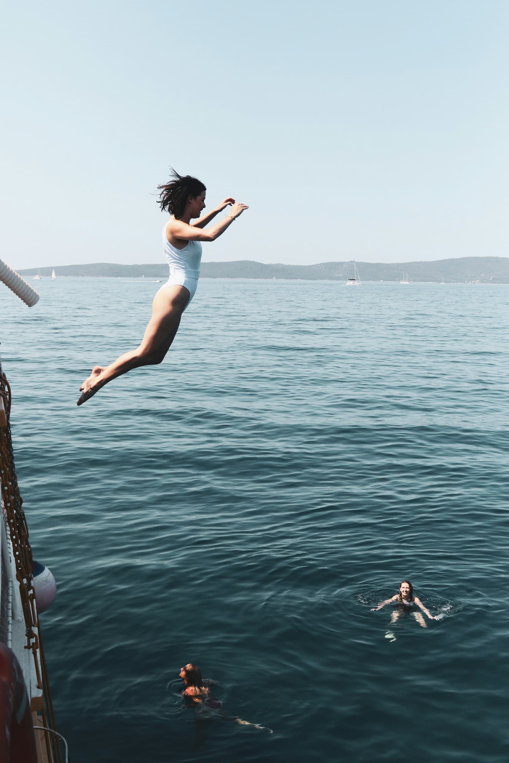 A swimmer leaping off the side of a boat into open water